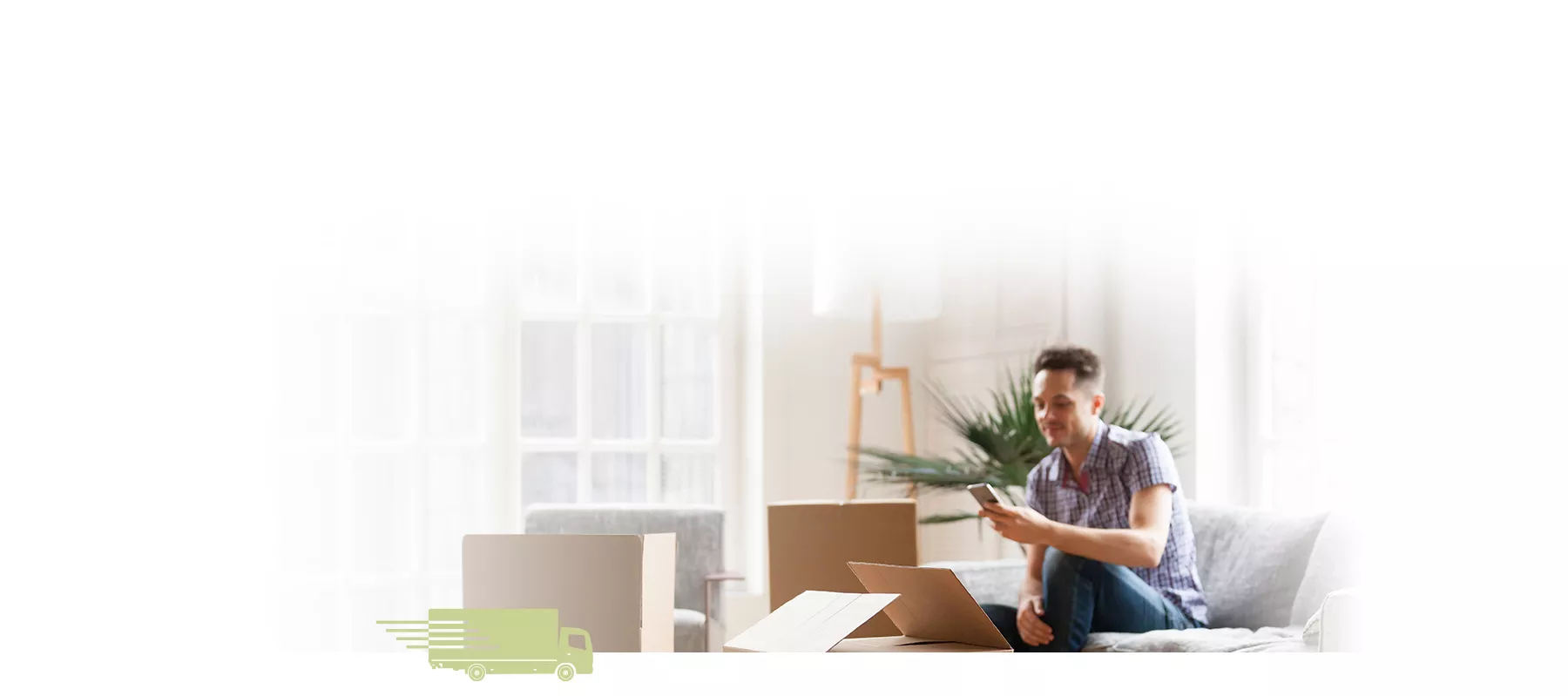 Guy looking at his phone inside a comfortable apartment with some open boxes around him